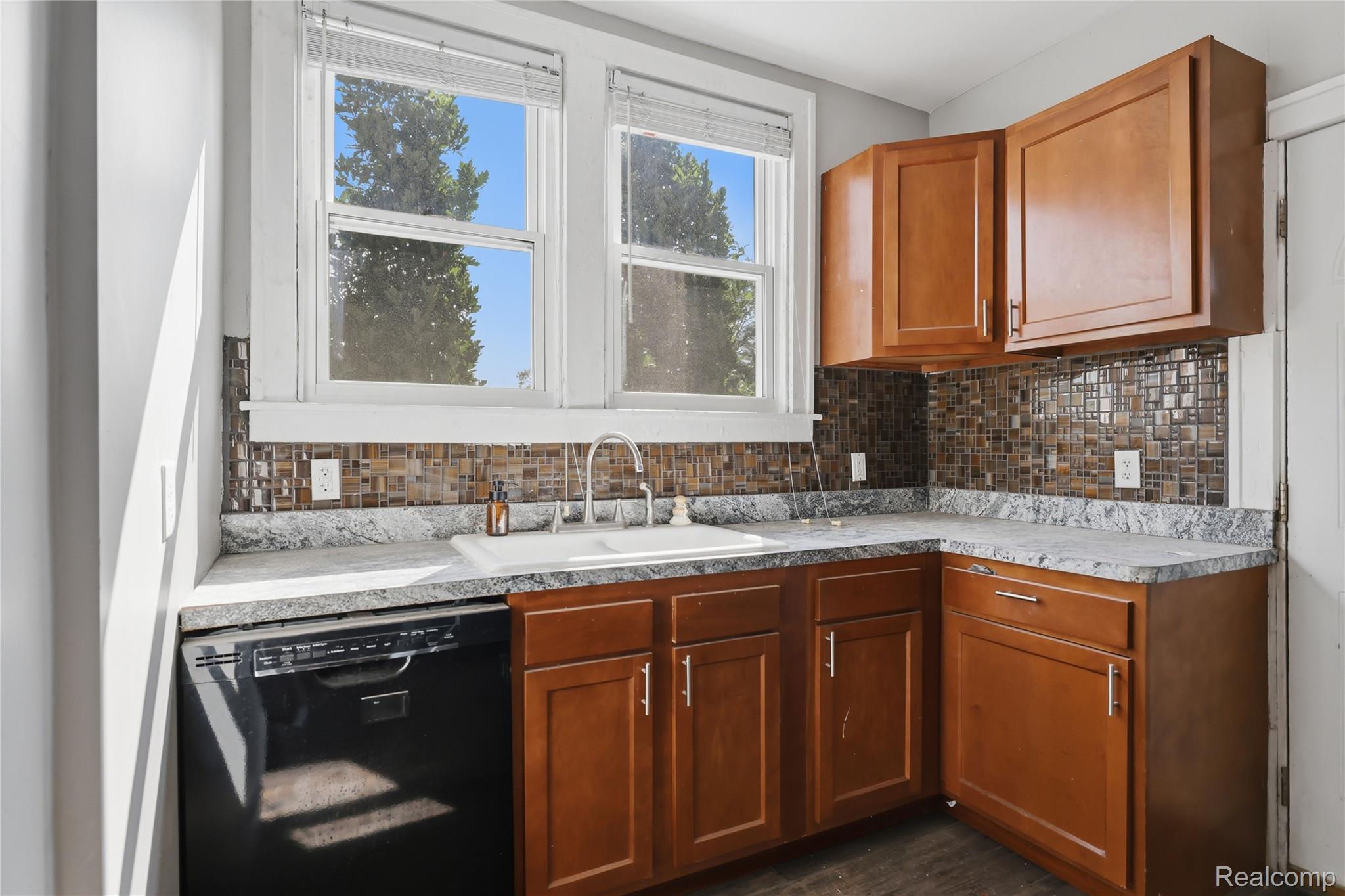 1945 Atkinson Street Detroit, MI 48206 - Photo 18 of 49 Kitchen featuring wood-finish cabinetry, speckled countertops, and a mosaic tile backsplash
