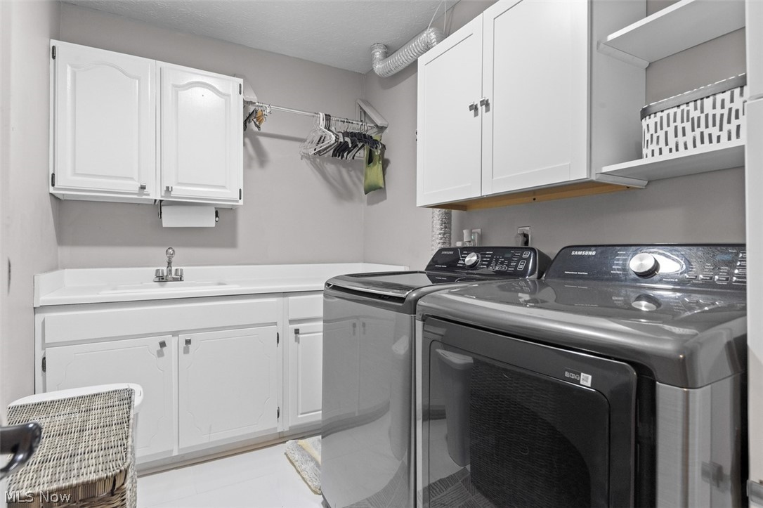 171 Granger Road, Unit 107 Medina, OH 44256 - Photo 22 of 41 Functional laundry room featuring white cabinetry, an integrated sink with a chrome faucet, and ample counter & closet space.