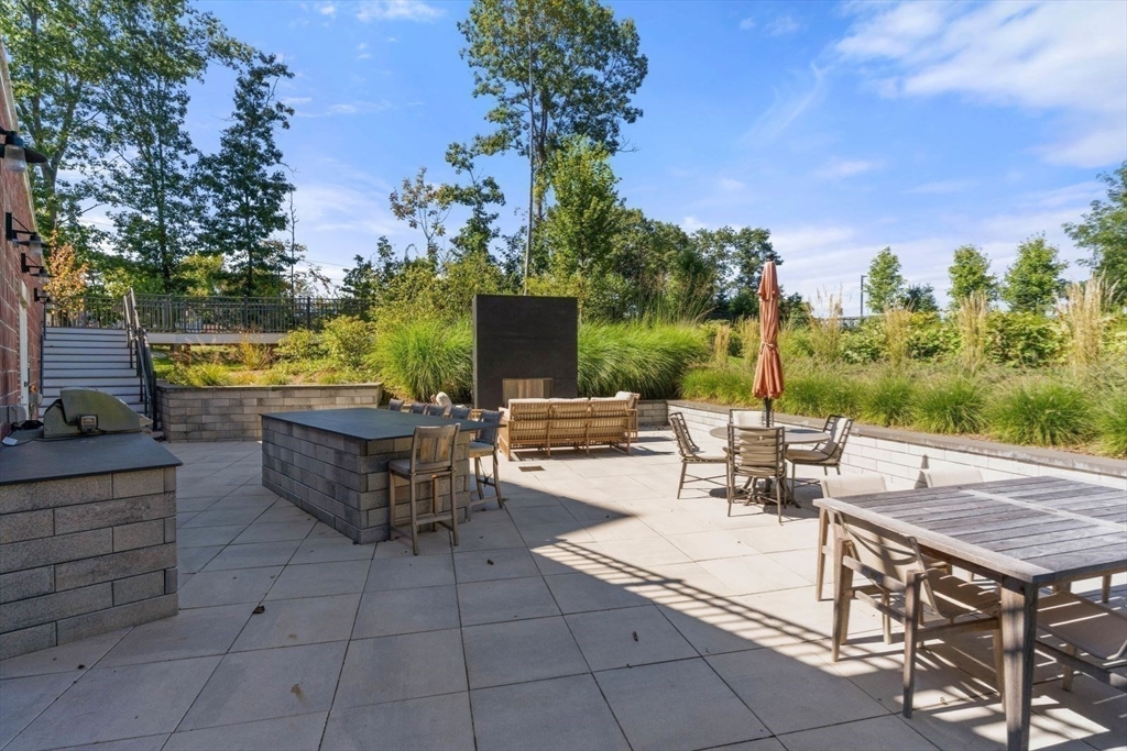 60 Coppersmith Way, Unit 304 Canton, MA 02021 - Photo 31 of 42 a view of a patio with dining table and chairs with a fire pit and a fire pit