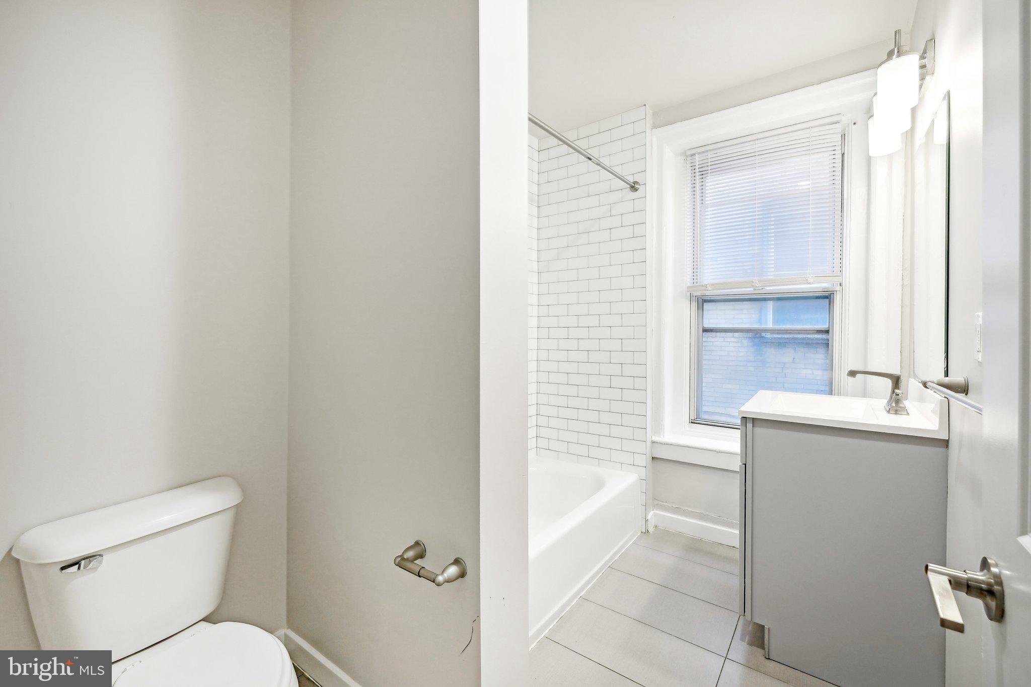 4300 Chestnut Street, Unit 1 Philadelphia, PA 19104 - Photo 12 of 30 a bathroom with a granite countertop toilet sink and mirror