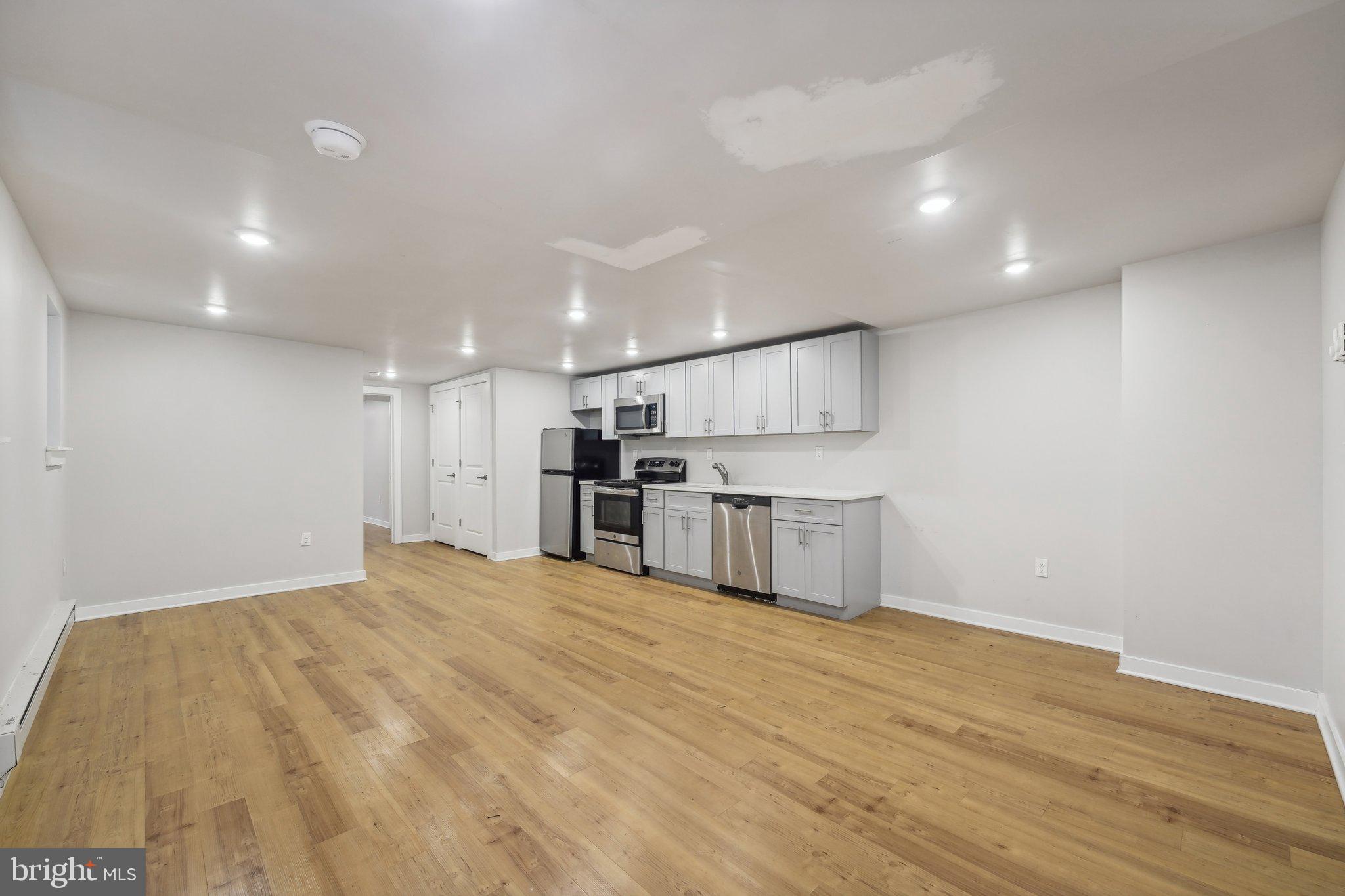 4300 Chestnut Street, Unit 1 Philadelphia, PA 19104 - Photo 4 of 30 a large white kitchen with kitchen island a sink stainless steel appliances and cabinets