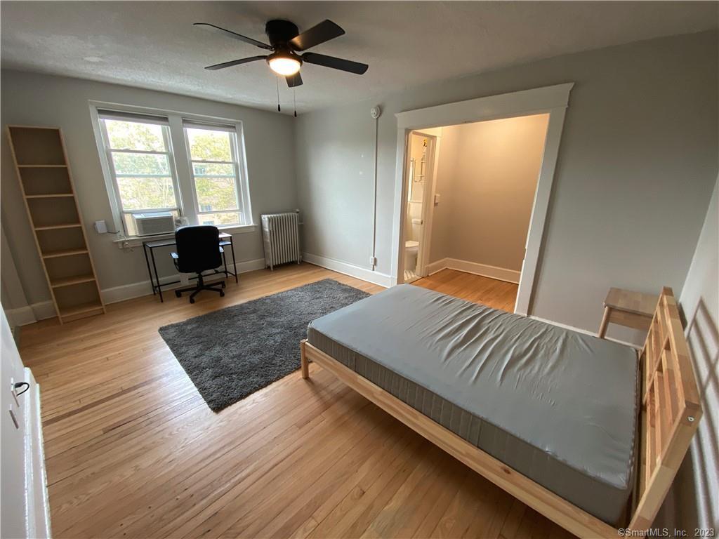 a bedroom with a bed windows and wooden floor