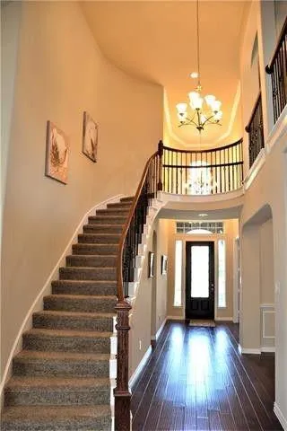 a view of staircase with wooden floor and a chandelier