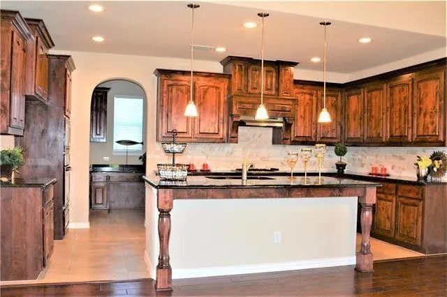 a kitchen with stainless steel appliances granite countertop a refrigerator a sink dishwasher a stove and white countertops with wooden floor