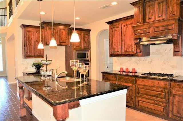 a kitchen with stainless steel appliances granite countertop a sink a stove and a refrigerator
