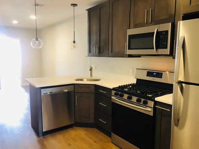 a kitchen with stainless steel appliances a stove a microwave and a sink