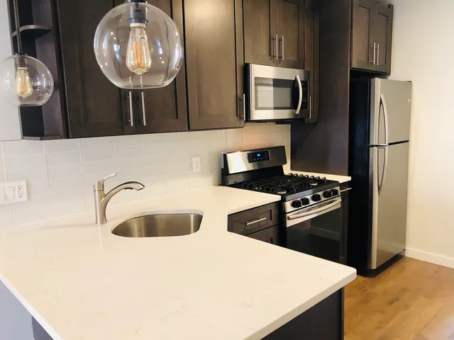 a kitchen with stainless steel appliances granite countertop a sink a stove microwave and refrigerator