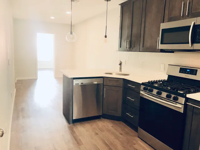 a kitchen with stainless steel appliances granite countertop a stove a sink and a microwave