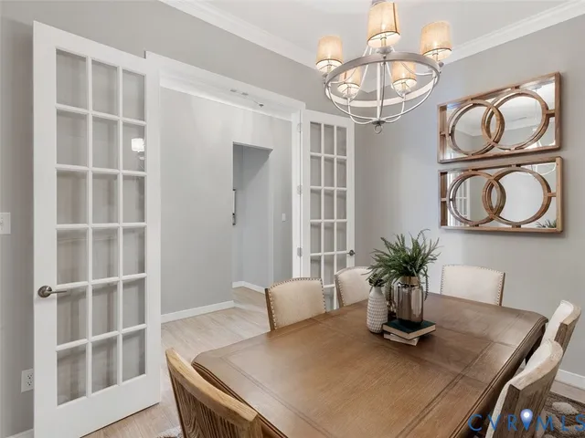 a dining room with wooden floor a chandelier a glass table and chairs