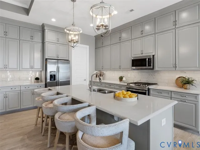 a kitchen with stainless steel appliances granite countertop a sink a stove a refrigerator cabinets and chairs