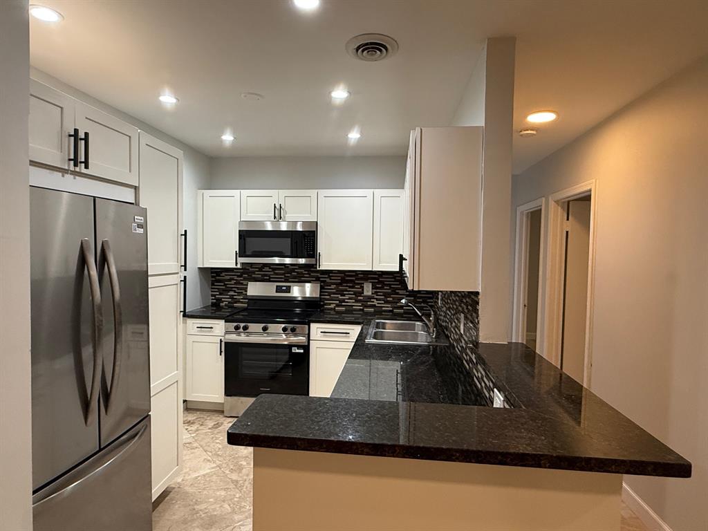 a kitchen with kitchen island a counter top space a stainless steel appliances and cabinets