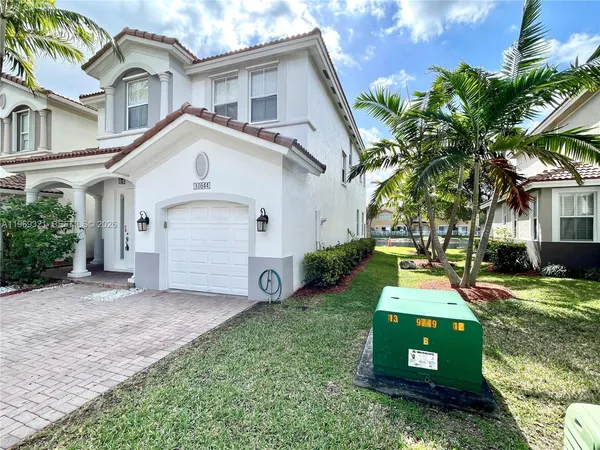 a view of a white house next to a yard and trees