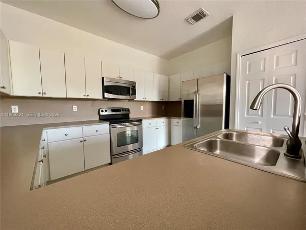 a kitchen with granite countertop a sink stainless steel appliances and cabinets