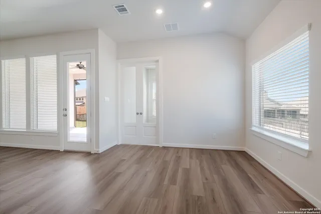 an empty room with wooden floor and windows