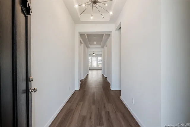 a view of a hallway with wooden floor and a chandelier