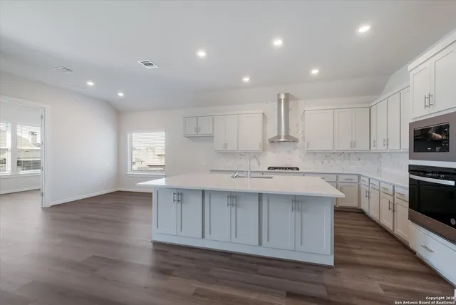 a large kitchen with stainless steel appliances granite countertop a sink and cabinets