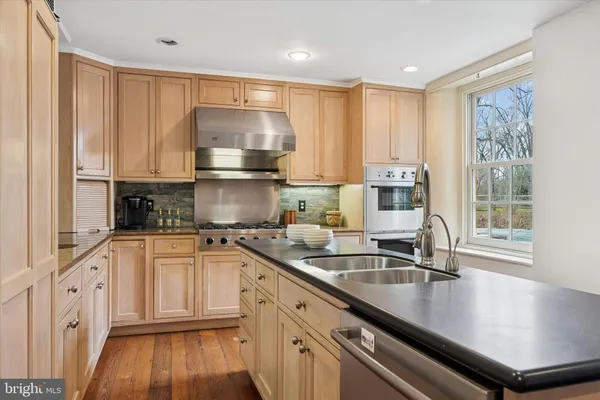 a kitchen with stainless steel appliances granite countertop a sink a stove and white cabinets
