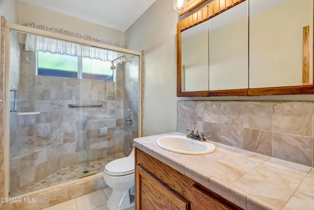 a bathroom with a granite countertop sink toilet and shower