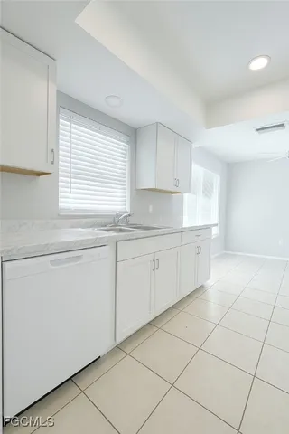a kitchen with white cabinets appliances a sink and a window
