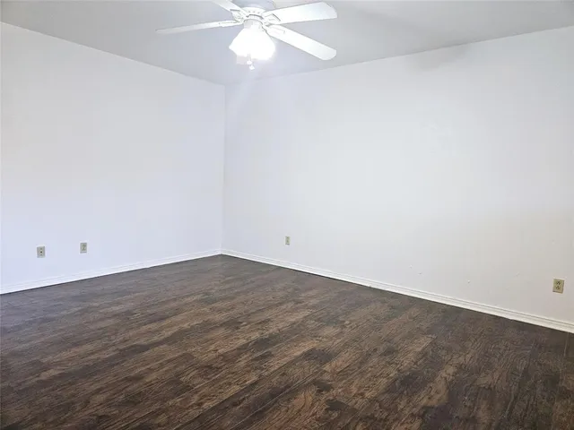 an empty room with wooden floor and fan