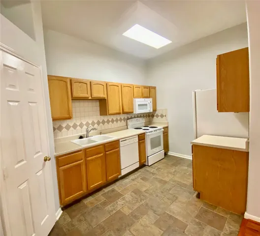 a large white kitchen with a sink a stove a refrigerator and a window