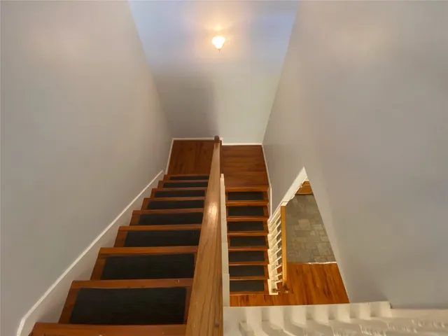 a view of staircase with wooden floor and white walls