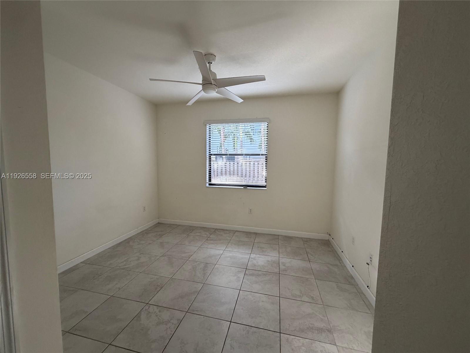 24886 Southwest 118th Avenue, Unit 24886 Homestead, FL 33032 - Photo 4 of 7 an empty room with a ceiling fan and window