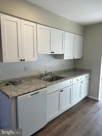 a kitchen with granite countertop white cabinets and sink