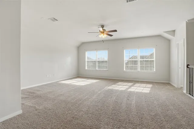 an empty room with windows and ceiling fan