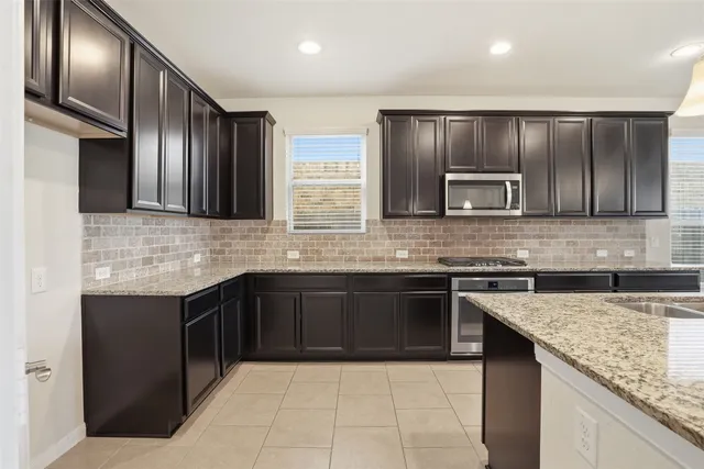 a kitchen with stainless steel appliances granite countertop wooden cabinets a granite counter tops and a stove