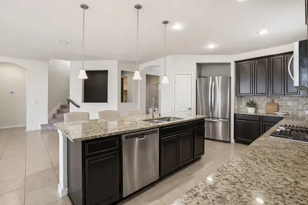 a kitchen with stainless steel appliances kitchen island granite countertop a sink and a refrigerator