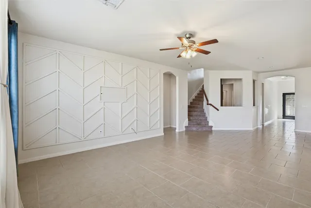 a view of an empty room with chandelier fan and wooden floor