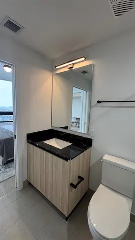 a bathroom with a granite countertop sink and a toilet