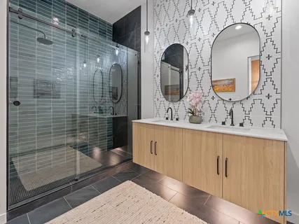 a bathroom with a double vanity sink mirror and shower