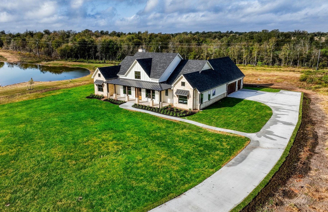an aerial view of a house with a garden and lake view
