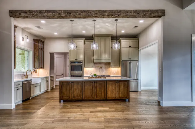 a large kitchen with stainless steel appliances a large counter top a stove and a refrigerator