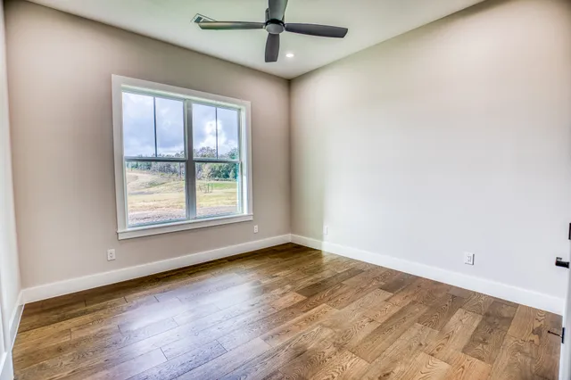 an empty room with wooden floor chandelier and windows