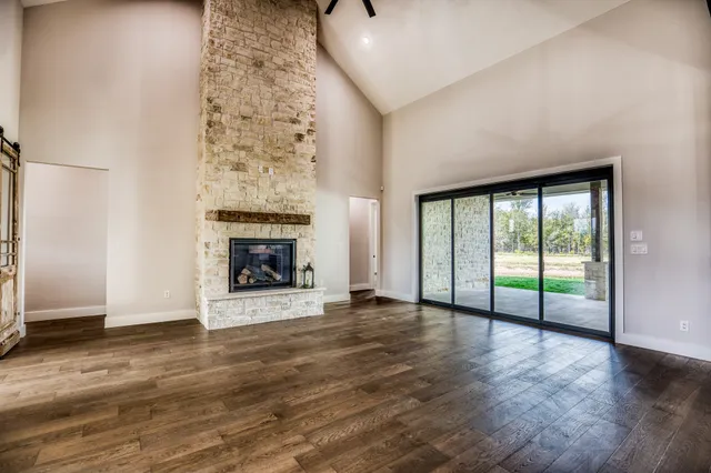 an empty room with wooden floor fireplace and windows