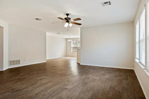 a view of an empty room with a window and wooden floor