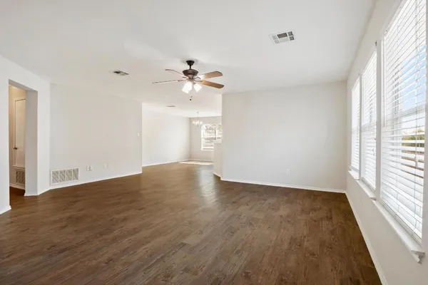 a view of an empty room with a window and wooden floor