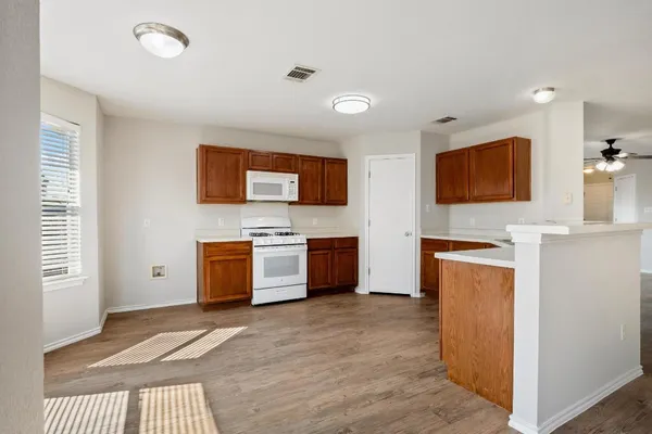 a large white kitchen with stainless steel appliances a stove a sink a refrigerator and a microwave