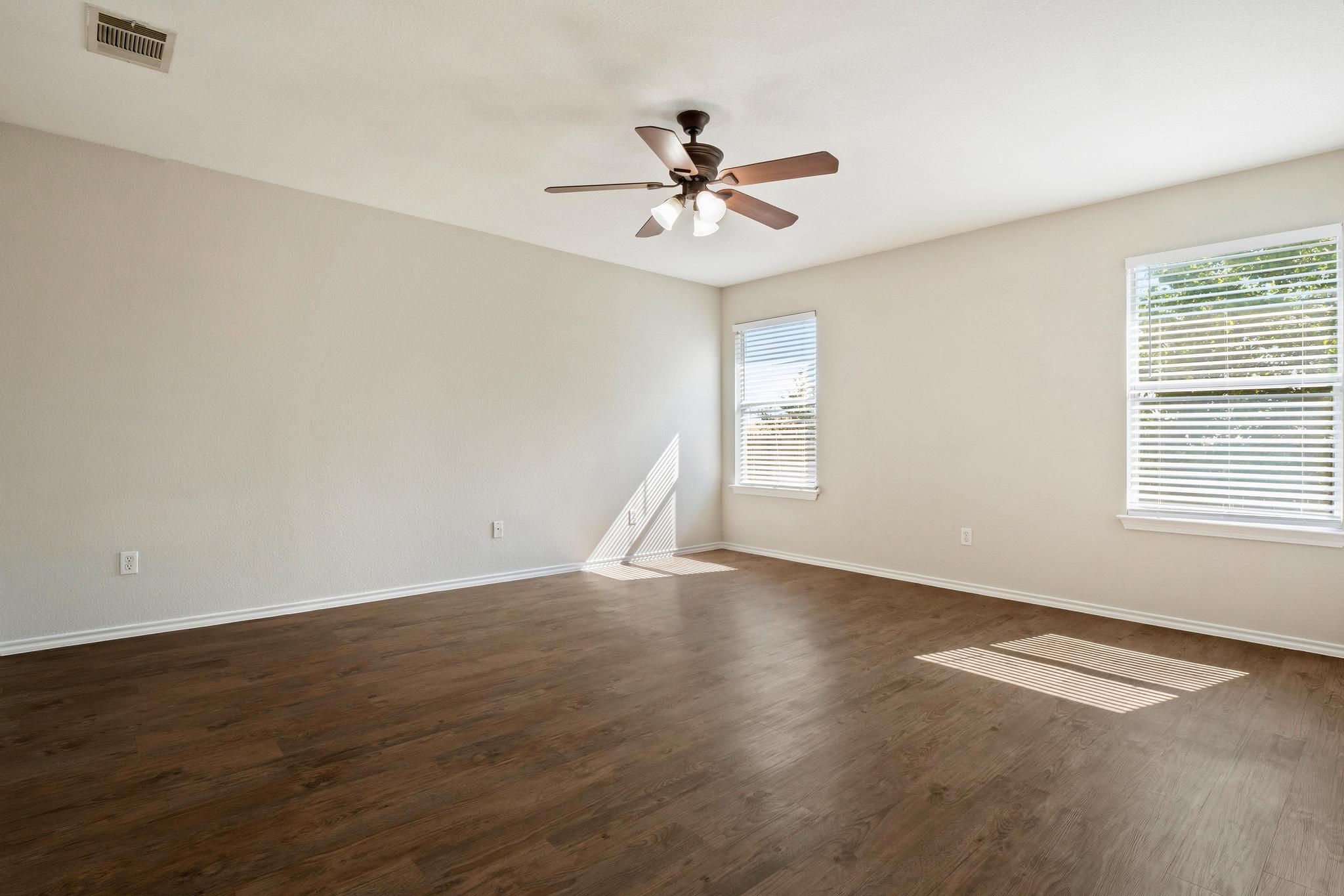 162 Brandons Way Buda, TX 78610 - Photo 30 of 36 an empty room with wooden floor chandelier fan and windows