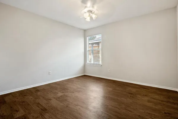 an empty room with wooden floor chandelier fan and windows
