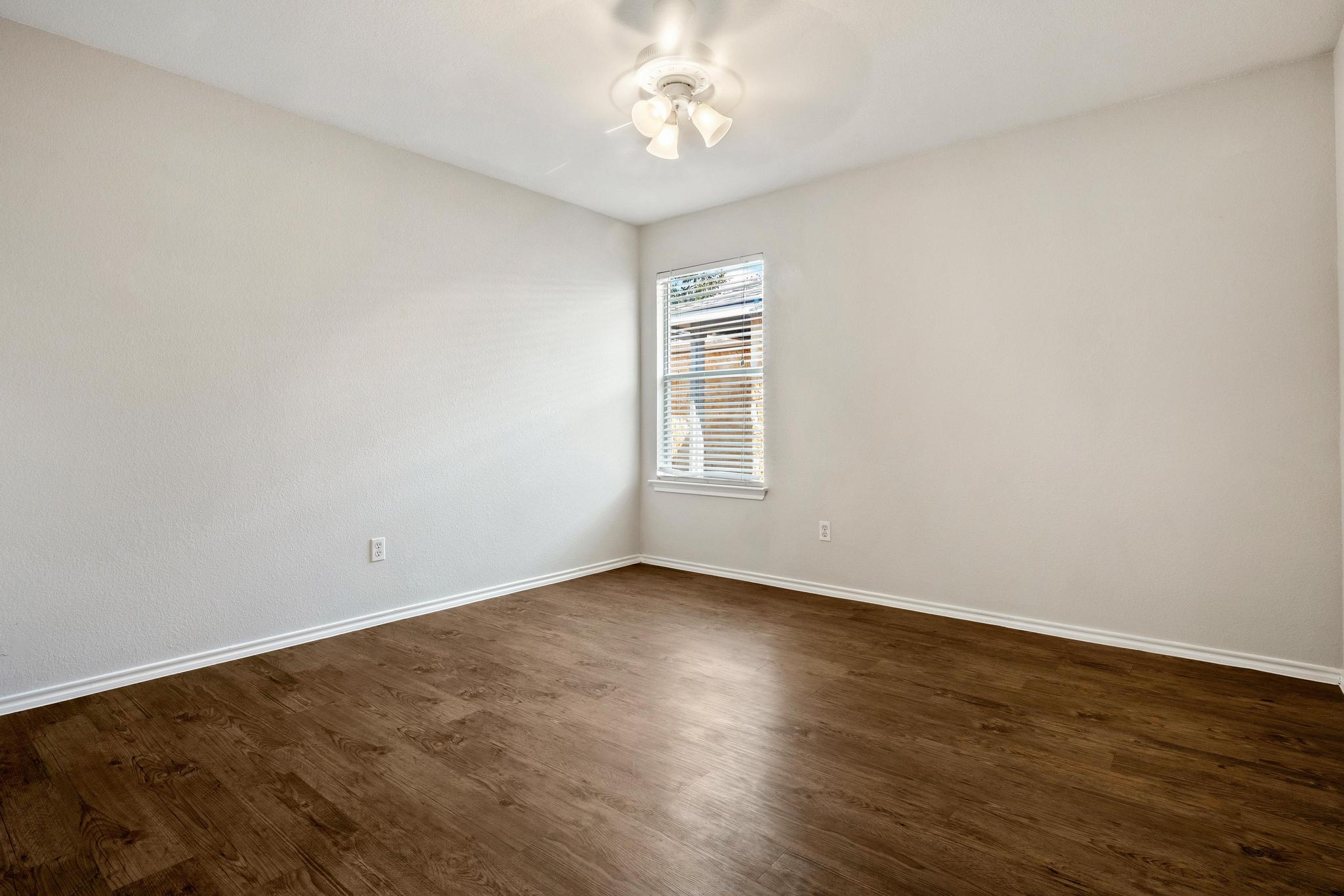 162 Brandons Way Buda, TX 78610 - Photo 36 of 36 an empty room with wooden floor chandelier fan and windows