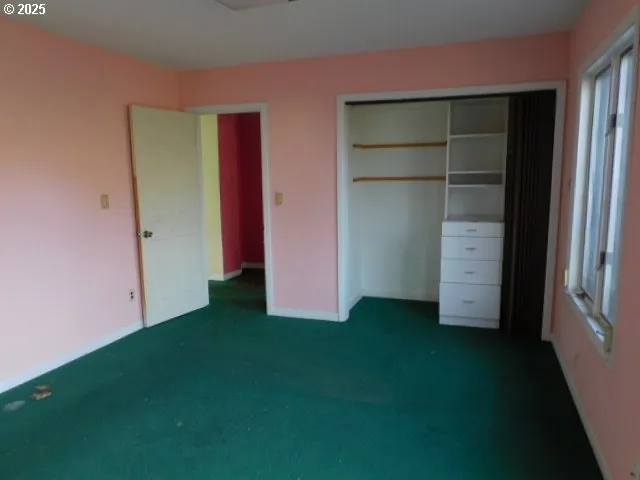 a view of an empty room with closet and a window
