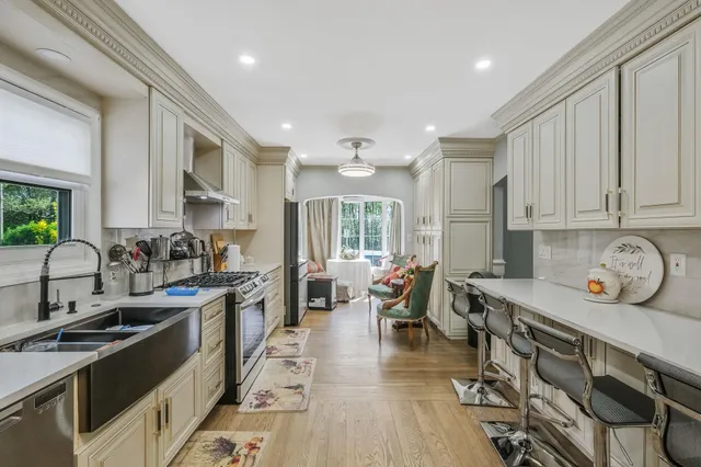 a kitchen with stainless steel appliances granite countertop a stove top oven a sink dishwasher a dining table and chairs with wooden floor