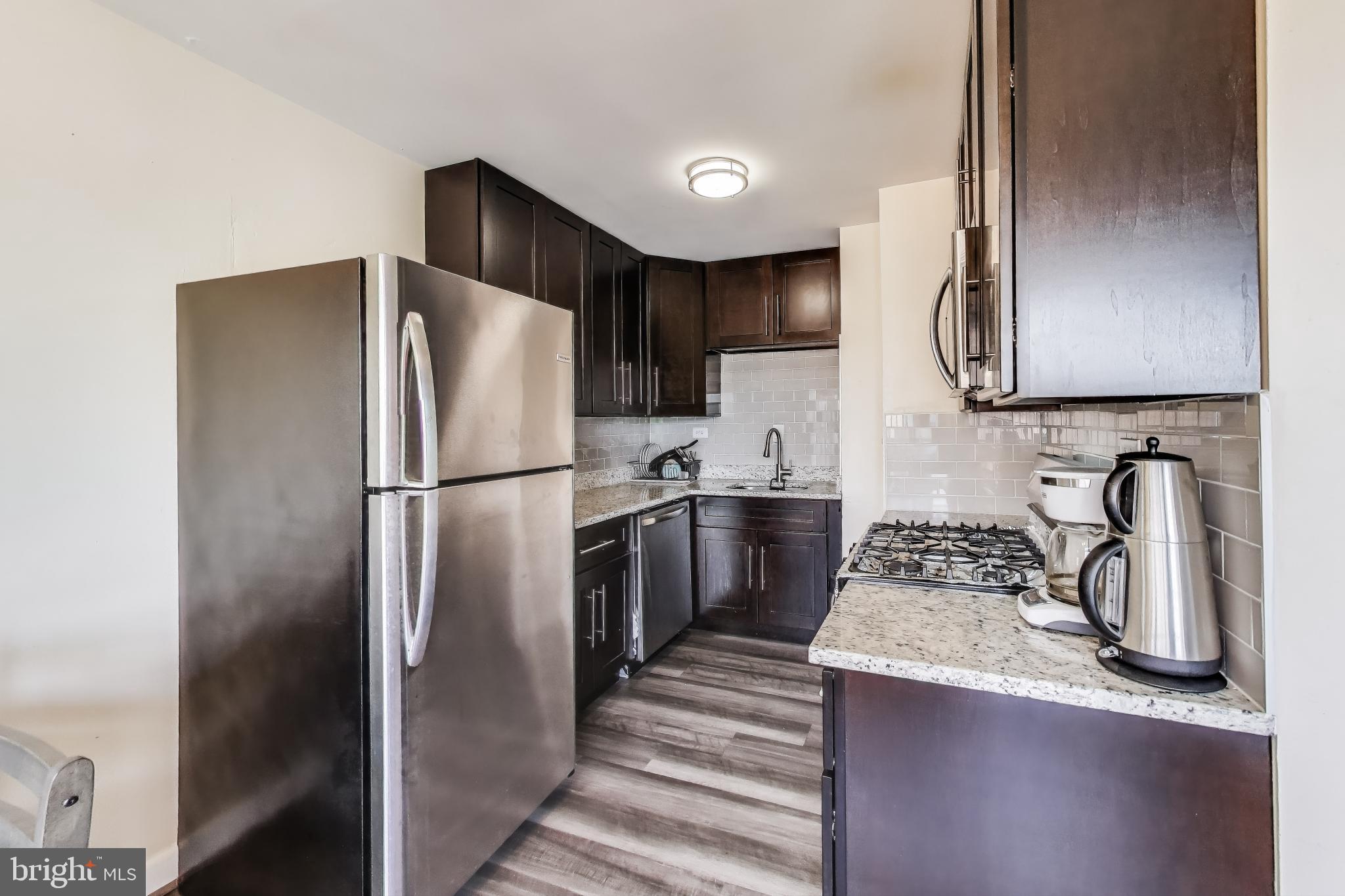 5851 Quantrell Avenue, Unit 407 Alexandria, VA 22312 - Photo 4 of 27 a kitchen with stainless steel appliances granite countertop a refrigerator a stove and a sink with wooden floor