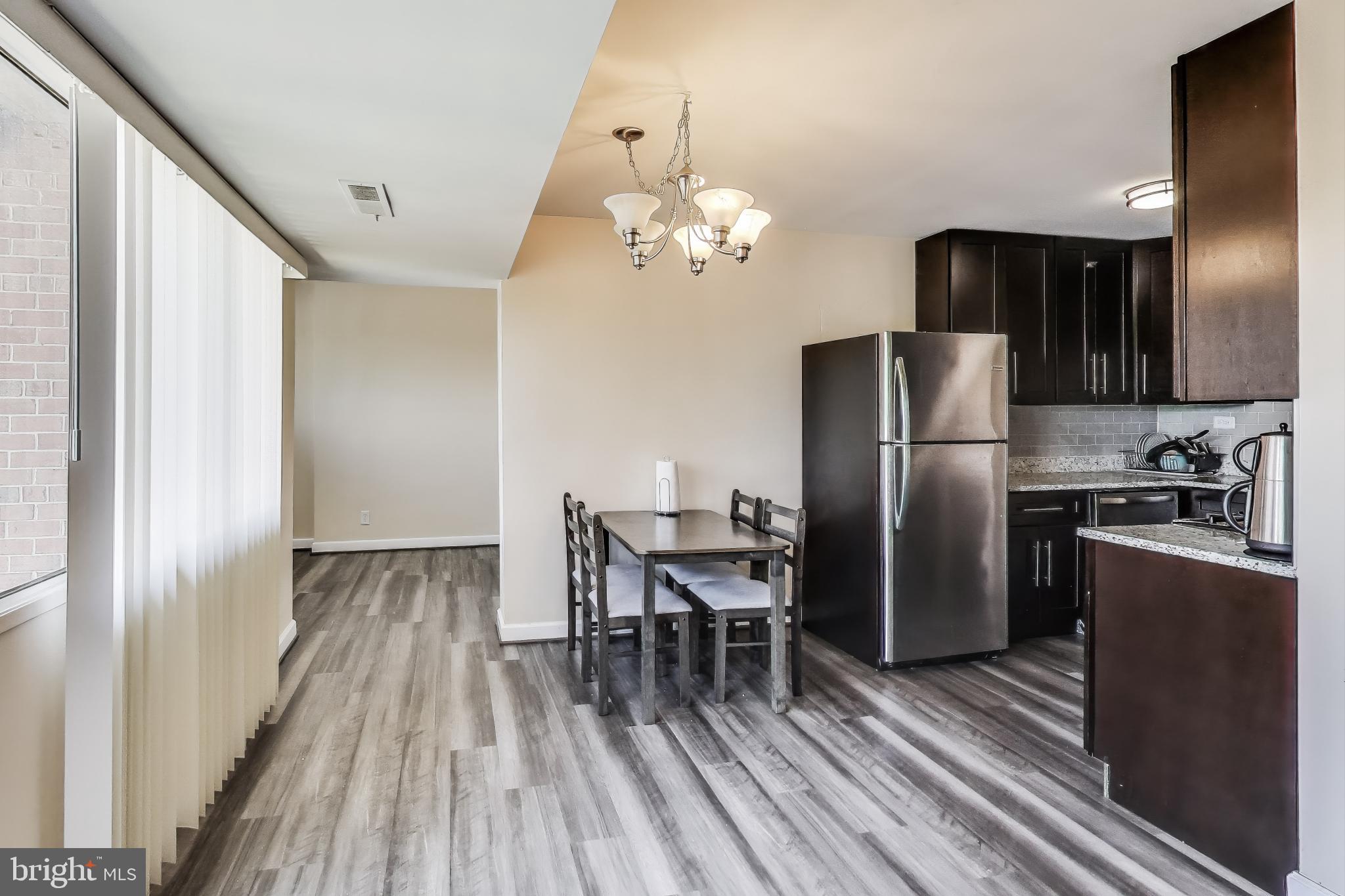 5851 Quantrell Avenue, Unit 407 Alexandria, VA 22312 - Photo 6 of 27 a kitchen with stainless steel appliances a refrigerator a sink dishwasher a stove and a dining table with wooden floor