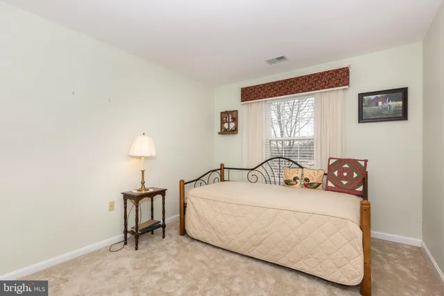 a bedroom with a bed and a lamp on dresser