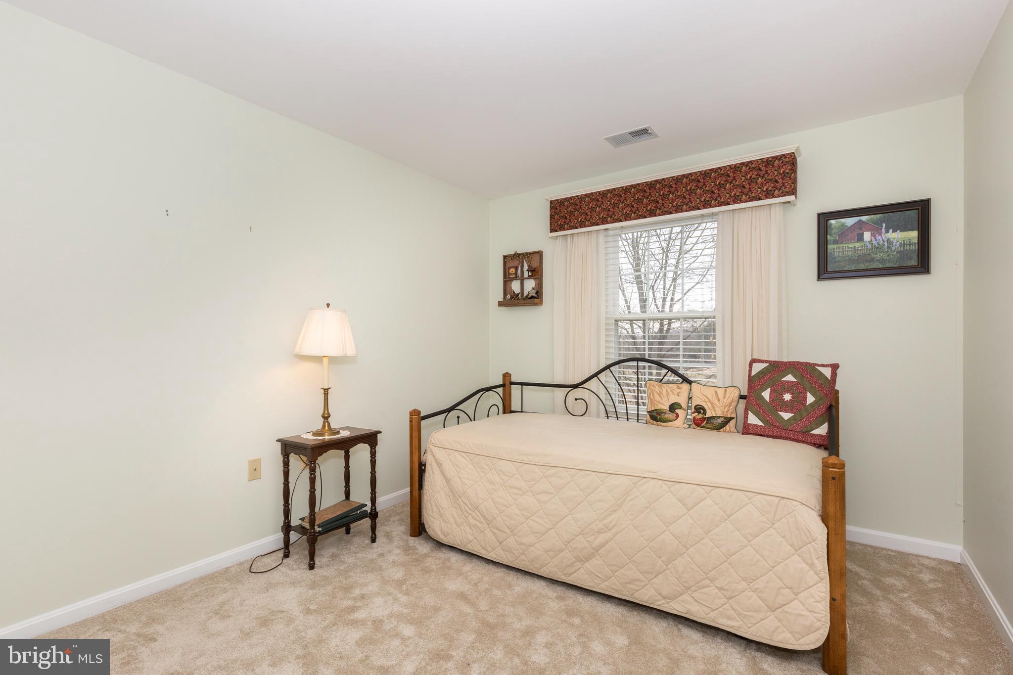 3850 Normandy Drive, Unit 2B Hampstead, MD 21074 - Photo 18 of 26 a bedroom with a bed and a lamp on dresser